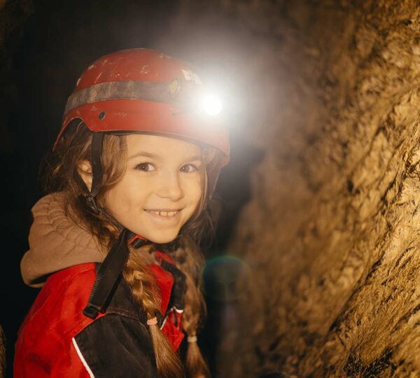 Mädchen mit Stirnlampe hofft in der Einhornhöhle darauf, die scheuen Fabelwesen zu entdecken.