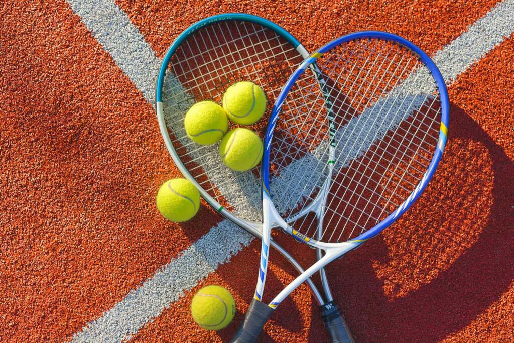 Tennisbälle und -schläger auf dem Tennisplatz liegend.